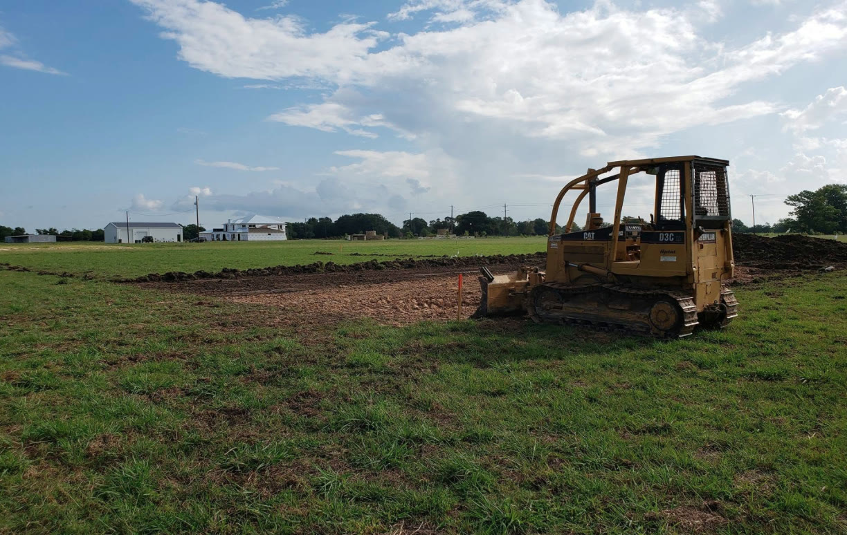 CAT D3C dozer cutting a house pad in an open field