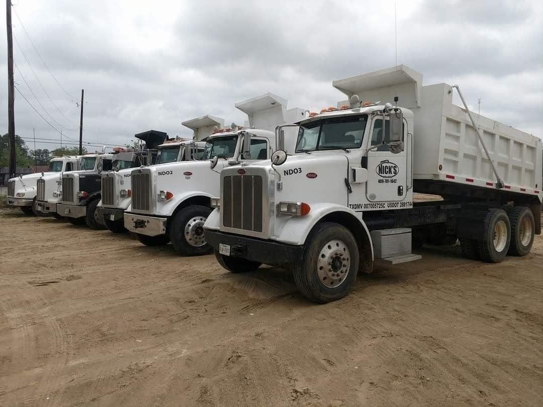 Row of white Nick's Dirt & Dozer Peterbilt dump trucks